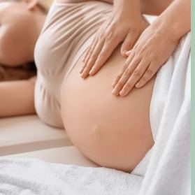 Deux mains posées sur le ventre d'une femme enceinte, lors d'un temps de massage et de détente.